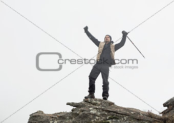 Man with hands raised on rock against the sky