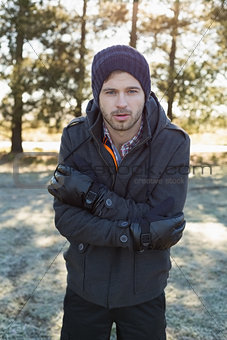 Man in warm clothing shivering while having a walk in forest