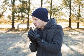 Man in warm clothing shivering while having a walk in forest