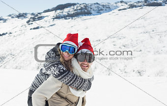 Man piggybacking cheerful woman on snow