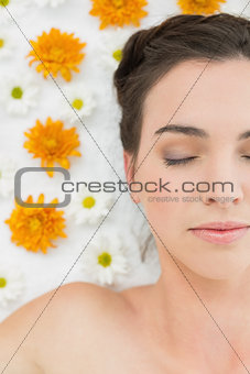 Beautiful young woman with eyes closed and flowers in beauty salon