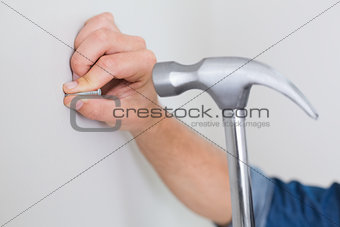 Extreme Close up of hand hammering nail in wall