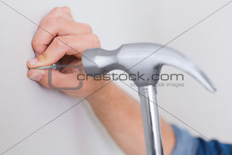 Hands hammering nail in wall