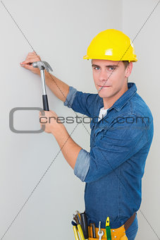 Portrait of handyman hammering nail in wall