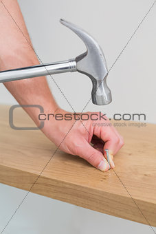 Hands hammering nail in wooden bench