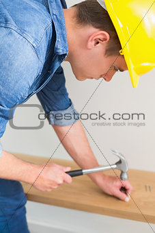 Handyman hammering nail in wooden bench