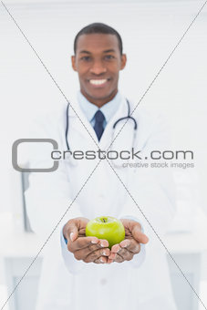 Male doctor holding a green apple at medical office