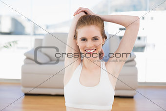 Woman stretching hands behind back in fitness studio