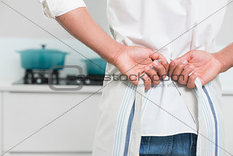 Mid section of man wearing apron in the kitchen