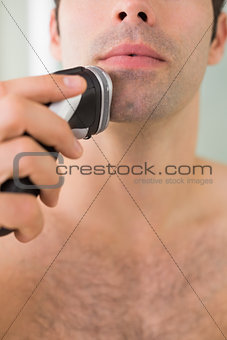 Extreme Close up of shirtless man shaving with electric razor