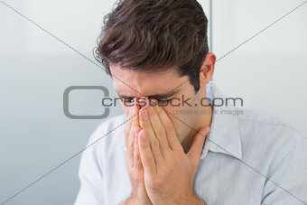 Sad casual young man with hands to his face