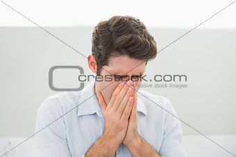Sad casual young man with hands to his face