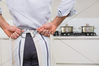 Mid section of man wearing apron in kitchen