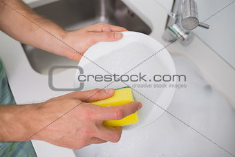 Hands doing the dishes at kitchen sink