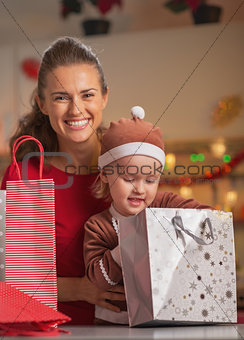 Portrait of happy mother and baby checking christmas shopping ba