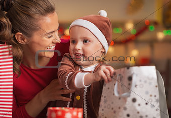 Happy mother and baby checking christmas shopping bags
