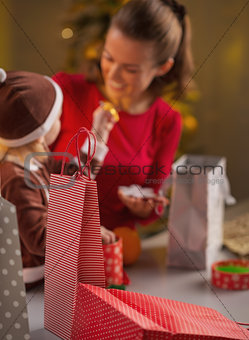Closeup on christmas shopping bags and mother and baby in backgr