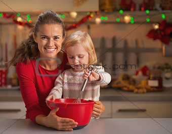 Baby helping mother make christmas cookies