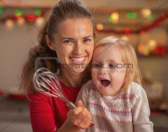 Portrait of happy mother and surprised baby looking on whisk