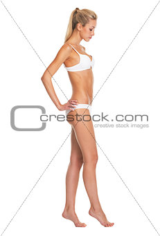 Full length portrait of young woman in lingerie going sideways