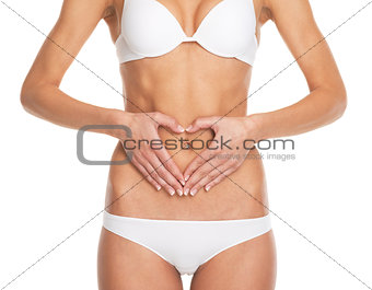 Closeup on young woman in lingerie put hands on stomach in form 