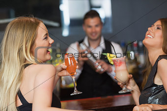 Handsome bartender working while gorgeous friends having cocktails