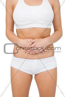 Mid section of young woman touching her belly with her hands