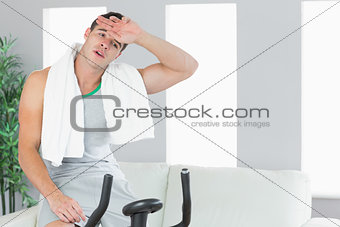 Exhausted handsome man exercising on exercise bike