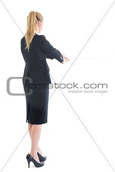 Rear view of standing business woman pulling a rope