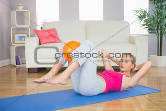 Sporty focused blonde doing sit ups holding ball between knees