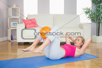 Sporty calm blonde doing sit ups holding ball between knees