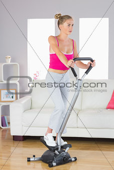 Sporty determined blonde training on step machine