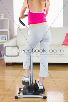 Rear view of sporty woman training on step machine