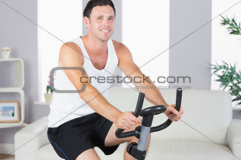Cheerful sporty man exercising on bike