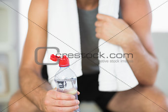 Close up of water bottle held by sporty man with towel