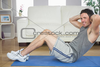 Handsome sporty man doing sit ups looking at camera