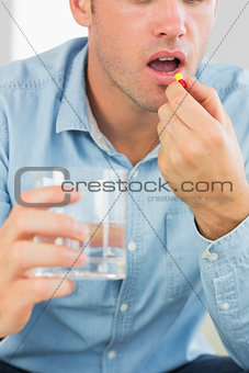 Close up of casual man taking a pill