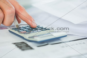 Close up of finger using calculator and holding pen