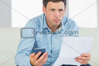 Serious casual man holding calculator and document