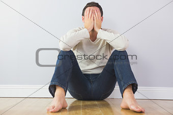 Casual upset man covering his face with hands