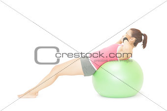 Attractive sporty brunette doing sit ups on exercise ball