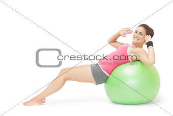 Smiling sporty brunette doing sit ups on exercise ball