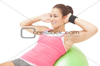Cheerful sporty brunette doing sit ups on exercise ball