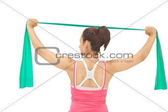 Rear view of sporty brunette stretching with resistance band