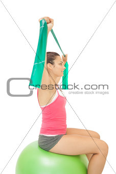 Smiling sporty brunette stretching with resistance band