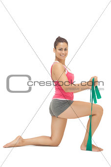 Smiling sporty brunette exercising with resistance band