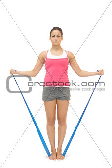 Serious sporty brunette exercising with resistance band