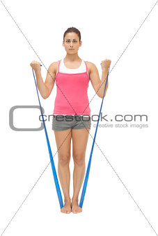 Stern sporty brunette exercising with resistance band