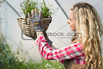 Happy woman fixing a hanging flower basket