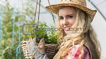 Smiling blonde touching a hanging flower basket